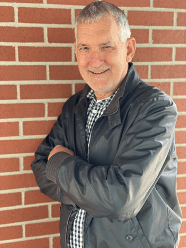 A man standing in front of a brick wall.