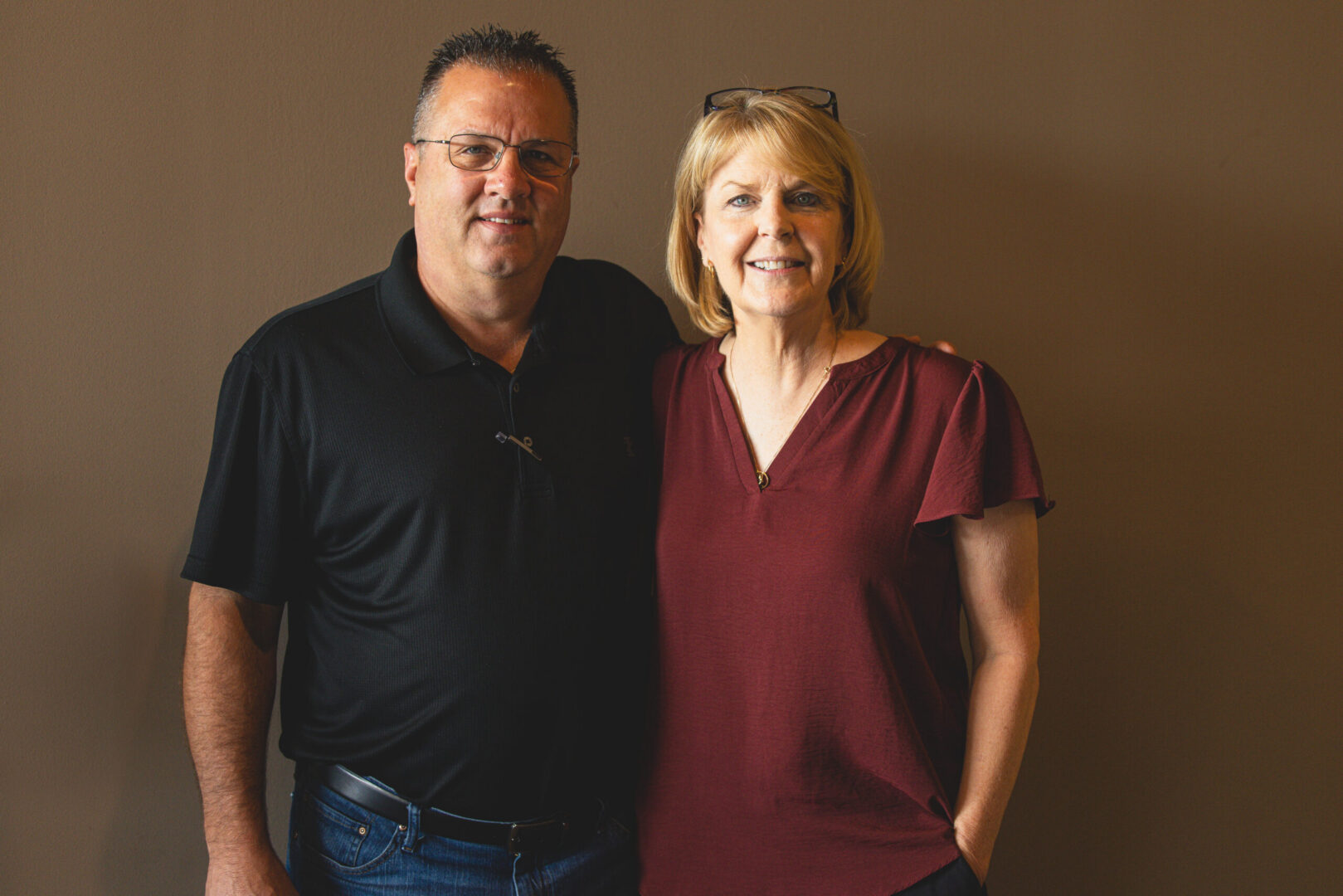 Smiling middle-aged couple standing against brown wall